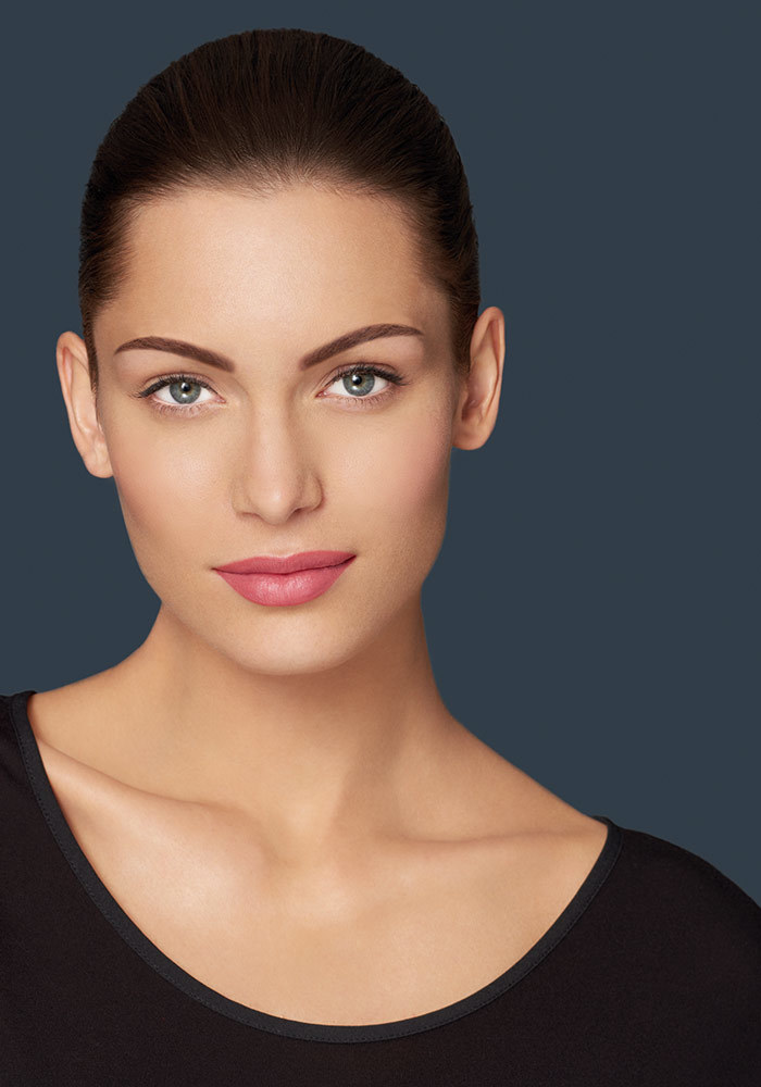 Portrait of a woman with permanent make up on her lips, on a grey background. 